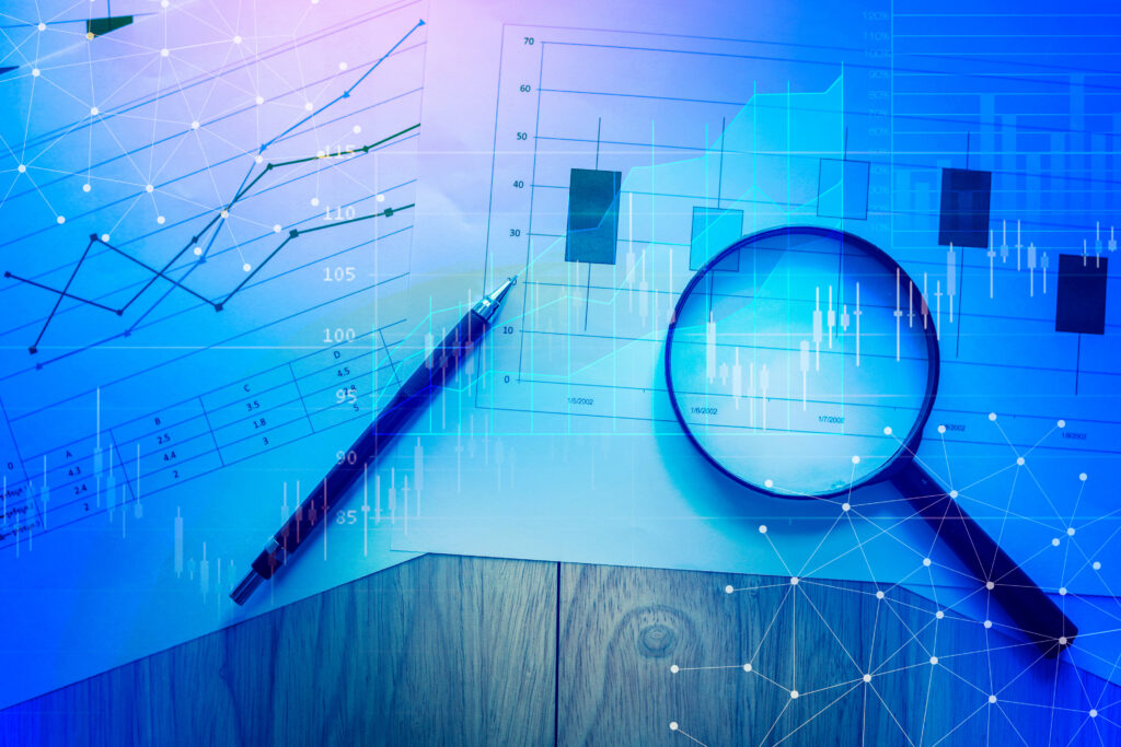 Magnifying glass and documents with analytics data lying on table,selective focus